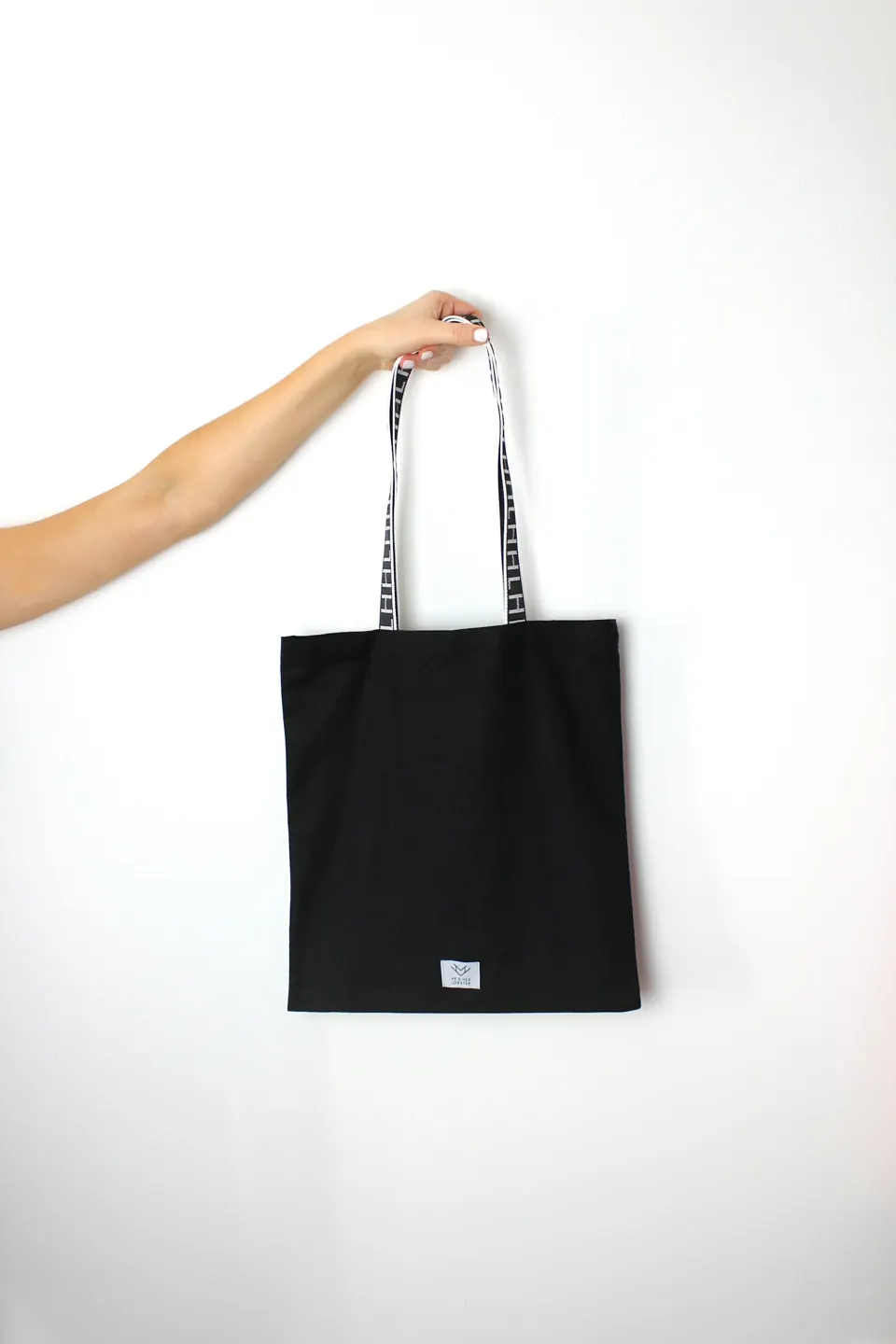 Black canvas tote bag held by its handles