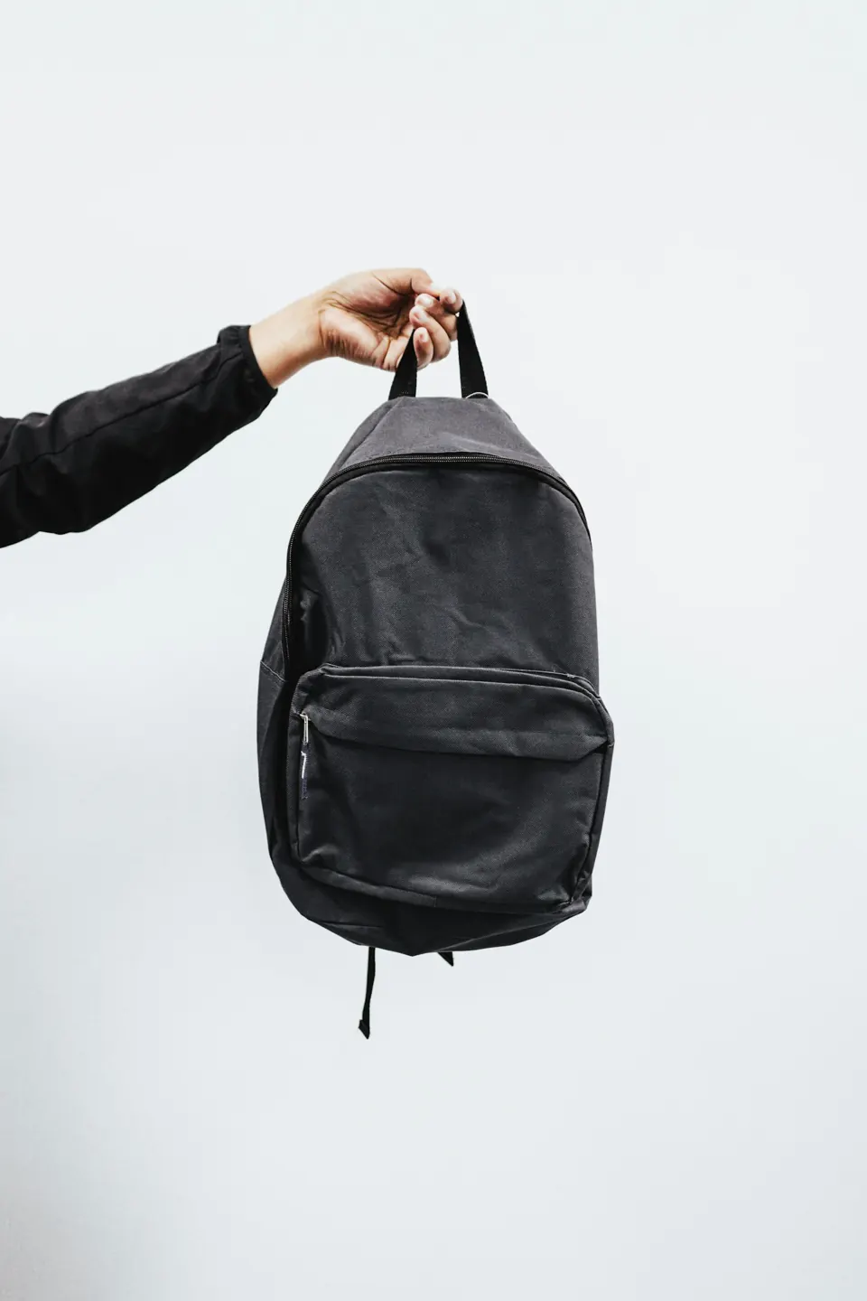 Person in black jacket holding black backpack