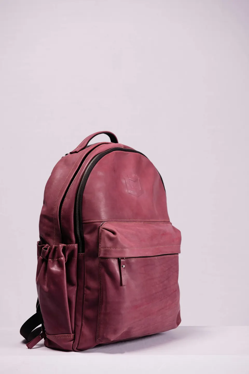 Red leather backpack on white wall