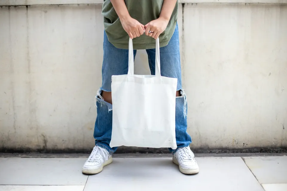Person holding white tote bag