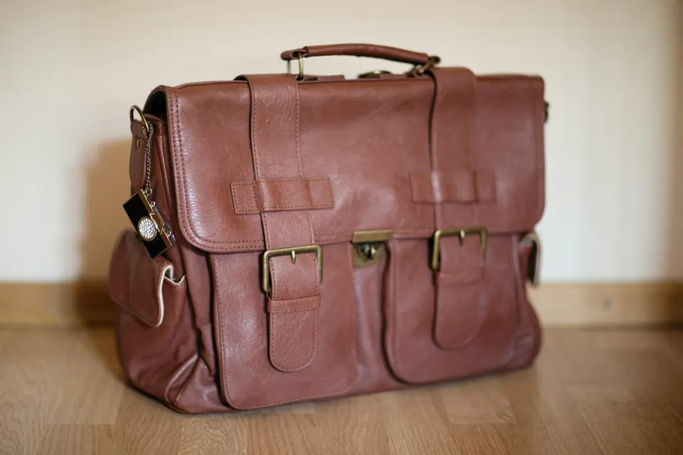 A brown leather briefcase sitting on top of a wooden floor