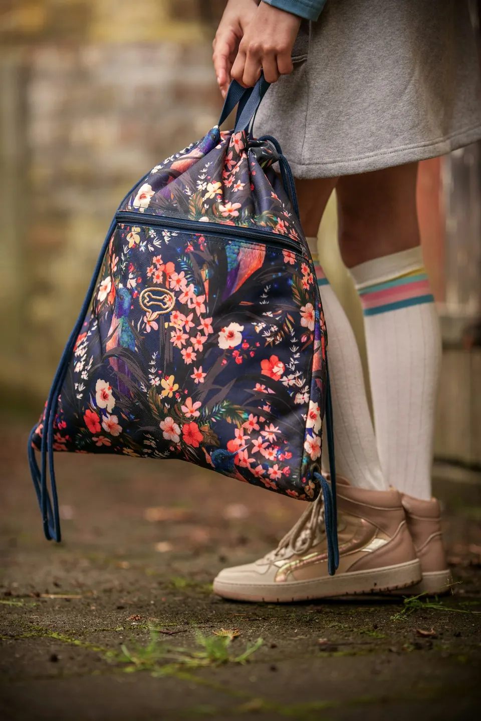 A girl holds a floral drawstring backpack