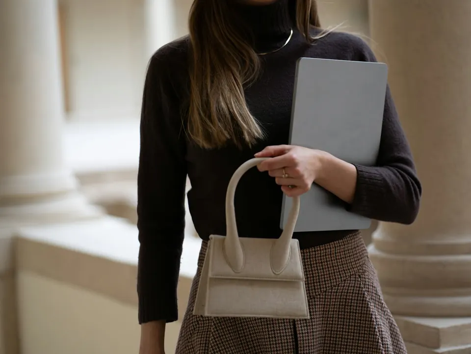 Woman holds a bag and a computer