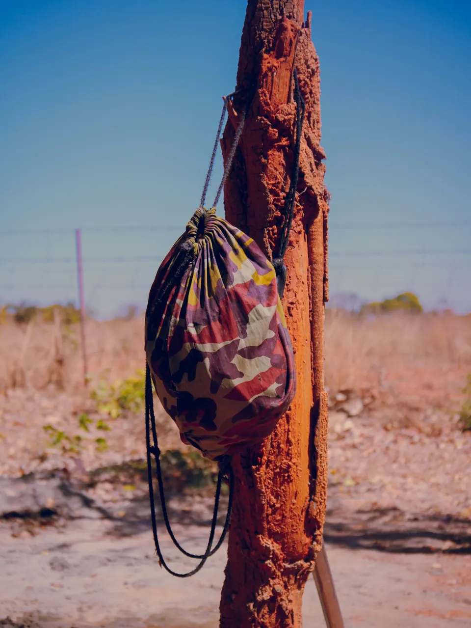 A camouflage drawstring bag hangs on a tree