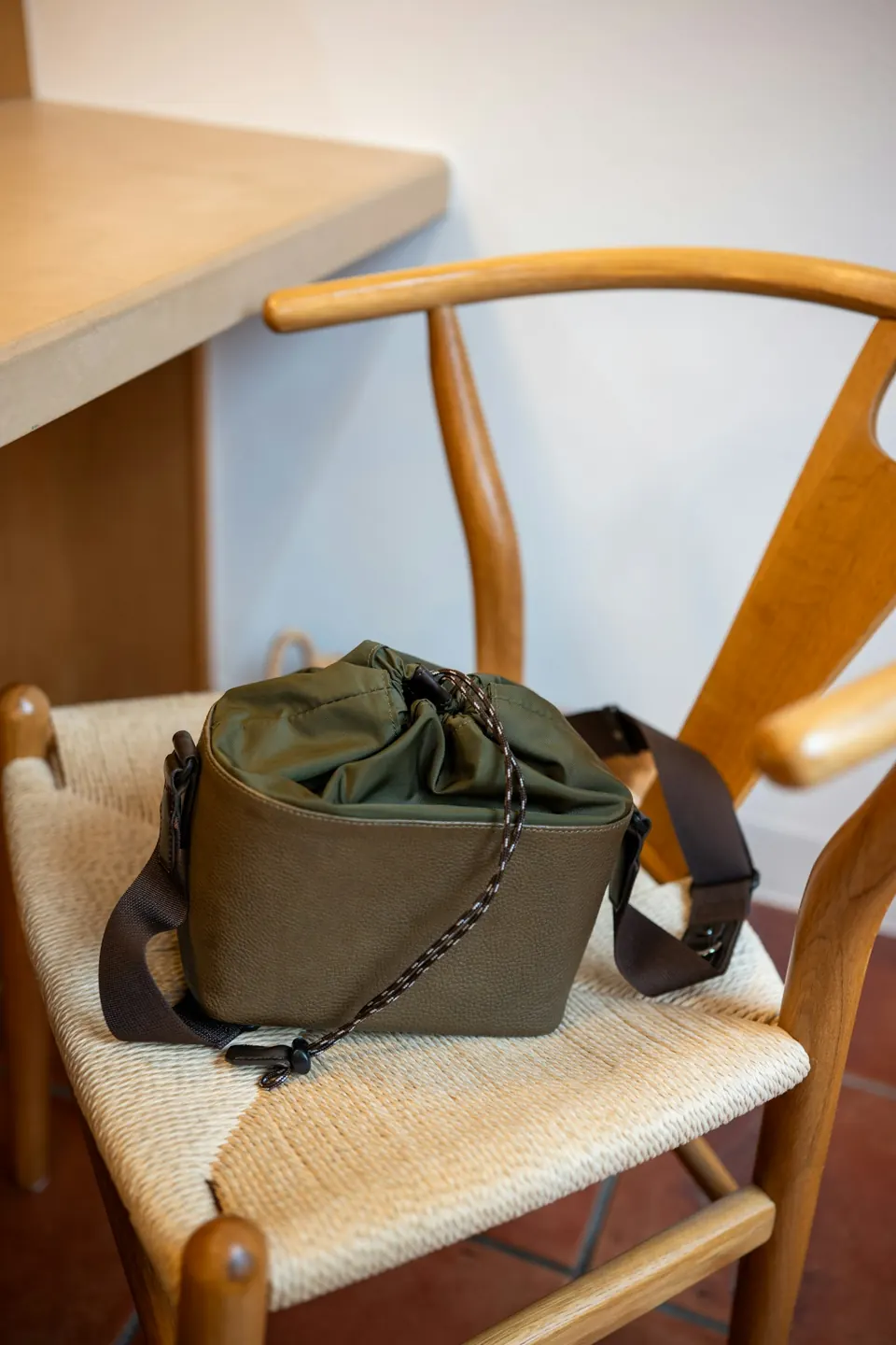 An olive green drawstring bag on a wooden chair
